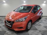 une Nissan Versa rouge garée sur un sol à damier dans un garage