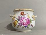a white vase with a pink rose on it on a table