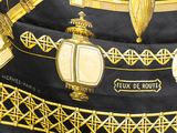 a black and gold scarf with a picture of lamps on it
