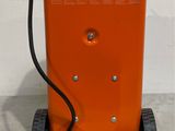 a close up of a small orange machine with a hose attached to it