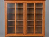 une bibliothèque en chêne avec des portes vitrées et des étagères