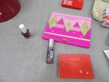 a pink box with lipstick, lipstick and other items on a table