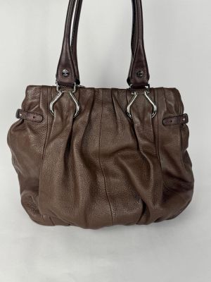un sac à main en cuir marron posé sur une surface blanche