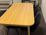 des tables et des chaises dans une pièce avec une fenêtre en arrière-plan