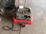 a red and black air compressor sitting on the ground