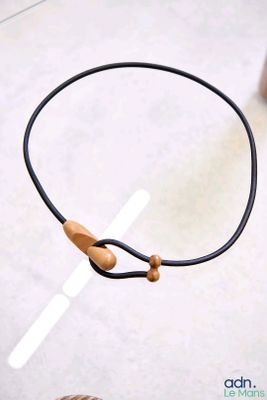 un cordon noir auquel est attachée une perle en bois