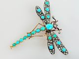 une photo d'une broche en forme de libellule, ornée de pierres turquoise et de diamants