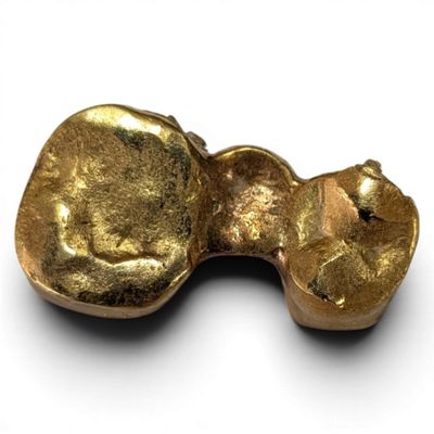 a gold object on a white surface with a white background
