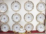 a display of china plates in a box with gold trimmings