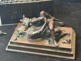 a bronze statue of a woman laying on a bed