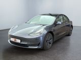 La Tesla Model 3 est garée dans une pièce au sol noir.