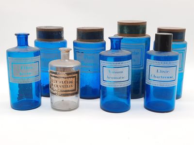 Plusieurs bouteilles contenant un liquide bleu sont alignées sur une surface blanche