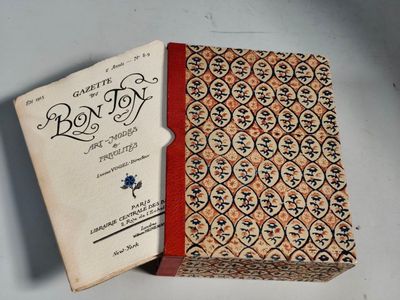an old book with a red cover sitting on top of a white table