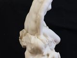 statue of a woman sitting on a rock on a black background