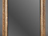 un miroir au cadre doré ouvragé sur fond gris