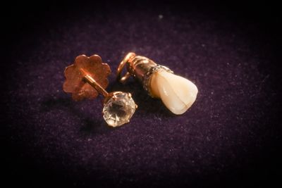 a close up of a pair of earrings on a purple surface