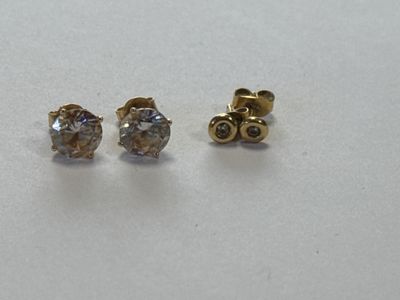 deux paires de boucles d'oreilles en diamant posées sur une surface blanche