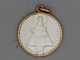 une image représentant un pendentif blanc et doré sur lequel figure une femme tenant un enfant dans ses bras
