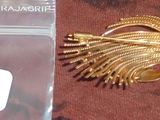 une photo d'une broche en or à laquelle est attachée une étiquette
