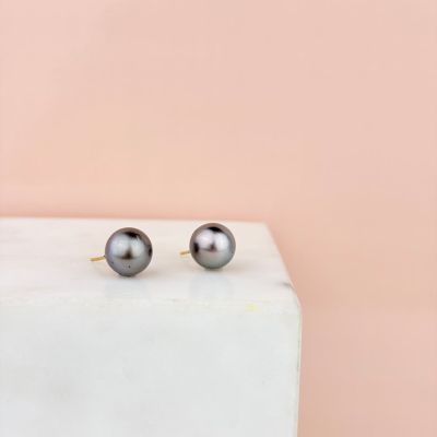 une paire de boucles d'oreilles en perles noires posée sur un bloc de marbre
