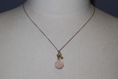 necklace with a pink rose pendant and a gold chain on a mannequin