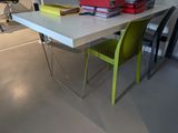 a white table with a green chair and a stack of books on it