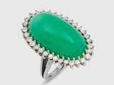 gros plan d'une bague avec une pierre verte entourée de diamants