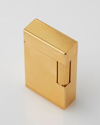 a gold cigarette lighter sitting on top of a white surface