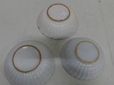 three white porcelain bowls with gold rims sitting on a white surface