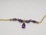 a necklace with purple stones and gold chains on a white surface