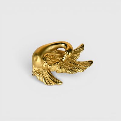 a close up of a gold bird brooch on a white background
