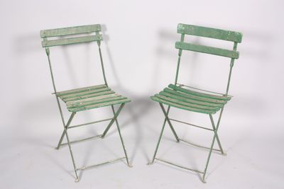 pair of green metal folding chairs against a white background