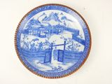 a blue and white plate with a picture of a village on it