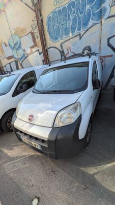 trois fourgonnettes blanches garées sur un parking, avec des graffitis sur le côté du bâtiment