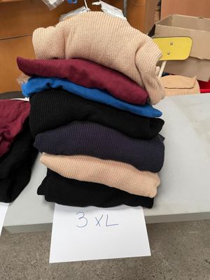 une pile de pulls posée sur une table, avec une étiquette de prix