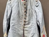 Une vieille veste bleue à col rouge est suspendue à un cintre.
