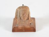 une photo d'une petite statue représentant une femme, posée sur un socle en bois