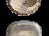 two silver trays sitting on top of each other on a black surface