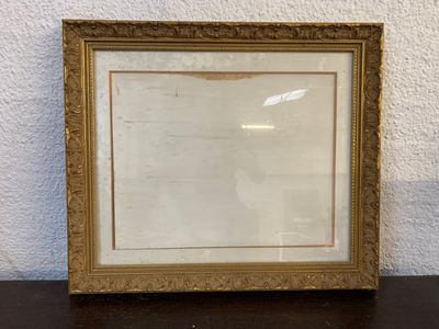 an old picture frame sitting on top of a table next to a white wall