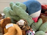 de nombreuses peluches dans une boîte en carton posée par terre