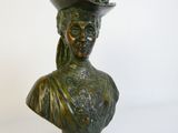 un buste en bronze représentant une femme coiffée d'un chapeau