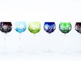 four wine glasses are lined up in a row on a white surface
