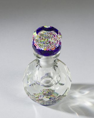 une petite bouteille en verre avec un bouchon violet et des paillettes dessus