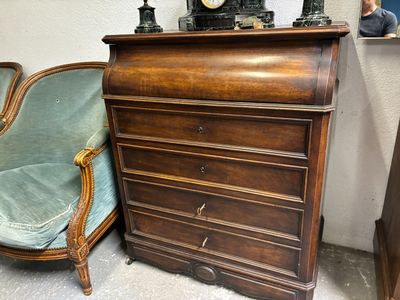 une commode sur laquelle est posée une horloge, à côté d'une chaise