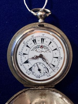 a silver pocket watch with roman numerals on it