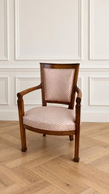 La chaise est en bois et dispose d'une assise rembourrée de couleur rose.