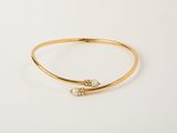 a gold bang bracelet with two pearls on it