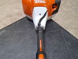 an orange stihl is sitting on the floor next to a piece of wood