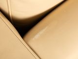 a close up of a tan leather couch with a white pillow