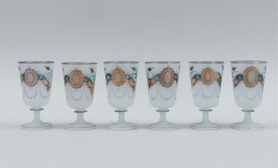 four white wine glasses with gold and blue designs on them
